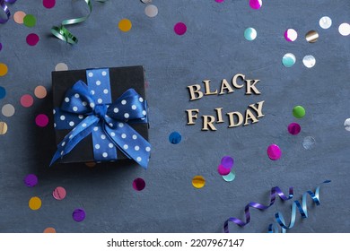 Black Friday Text With Gift And Holiday Tinsel Flat Lay On Dark Cement Background. Top View.