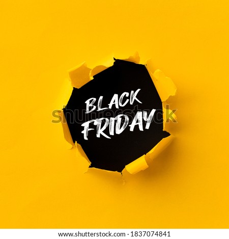 Black Friday text in paper hole teared in yellow paper over black background