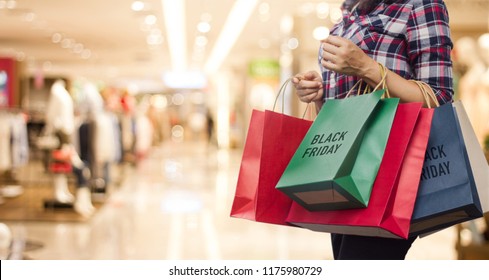 Black Friday, Woman holding many shopping bags while walking in the shopping mall background.