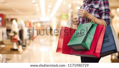 Black Friday, Woman holding many shopping bags while walking in the shopping mall background.