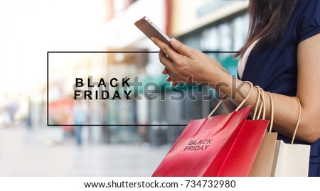 Black Friday, Woman using smartphone and holding shopping bag while standing on the mall background