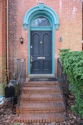 Black Front Door With Brick Staircase To An Old Red Brick House. Mailbox At The Entrance