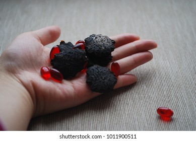 Black gac seeds and oil pills on neutral background.