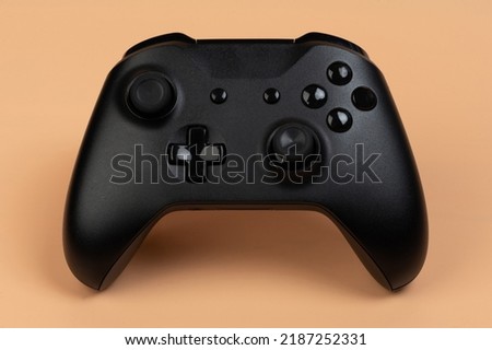 Black game controller front view isolated on brown background
