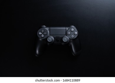 A black game controller isolated on black background.