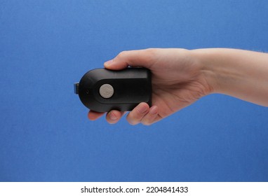 Black Garage Door Remote Opener Facing Camera In Hand On A Blue Background