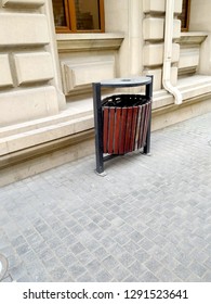 Black Garbage Bin Inside A Wooden Enclosure . Rubbish Box On The Road.