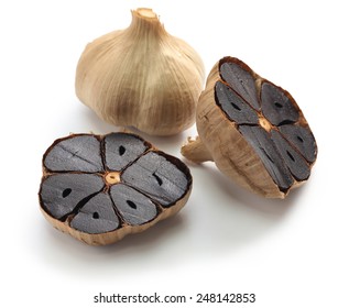 black garlic bulbs and cloves on white background