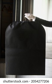 Black garment, suit travel bag. the hands of a hotel worker in white gloves.