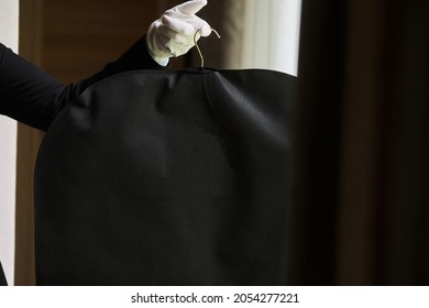 Black Garment, Suit Travel Bag. The Hands Of A Hotel Worker In White Gloves.