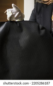 Black Garment, Suit Travel Bag. The Hands Of A Hotel Worker In White Gloves.