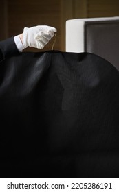 Black Garment, Suit Travel Bag. The Hands Of A Hotel Worker In White Gloves.