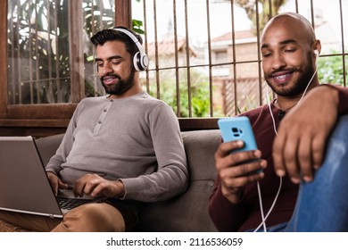 Black Gay Couple Relaxing And Using Mobile And Laptop In The Couch