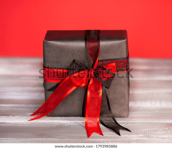 Black gift box with\
red and black ribbon.
