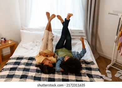 Black Girl And Her Mother Laughing And Talking While Lying On Bed At Home