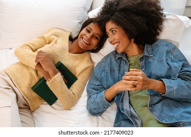 Black Girl And Her Mother Laughing And Talking While Lying On Bed At Home