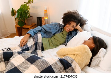 Black Girl And Her Mother Laughing And Talking While Lying On Bed At Home