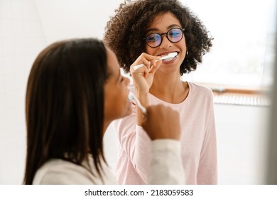 Black Girl And Her Mother Laughing While Brushing Their Teeth In Bathroom At Home