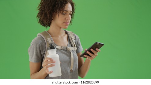 Black Girl Looks Around Holding Her Phone And Her Water Bottle On Green Screen