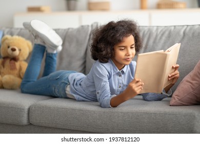 Black girl lying on the sofa, reading book