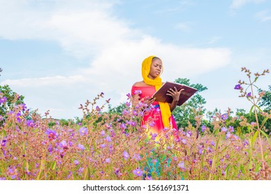 Black Girl Reading A Book Alone In A Field Of Flowers