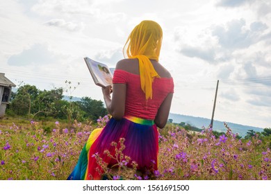 Black Girl Reading A Book Out In An Open Field, Wearing A Scarf