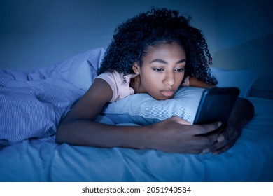 Black girl using smartphone in bed before sleeping - Shutterstock ID 2051940584