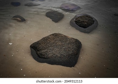 Black Glacial Rocks In The Shallow Seawater On Cape Cod