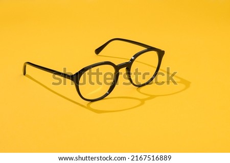 Black glasses office style in beautiful fashion yellow summer background. Eyeglasses plastic business or reading for promo sale and shopping