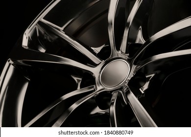 Black Gloss alloy wheel on a dark background. Stylish and expensive. Close-up of spoke elements,