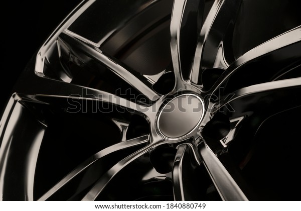 Black Gloss alloy wheel on a\
dark background. Stylish and expensive. Close-up of spoke\
elements,