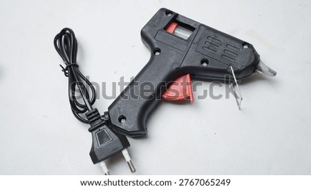 Black glue gun with red trigger and coiled power cord. White background highlights its industrial design. Ideal for crafting, DIY, or repair projects. No people, animals, or plants appear in the shot