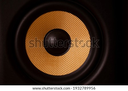 A black and gold coloured speaker cone.Shot with soft golden glow lighting.