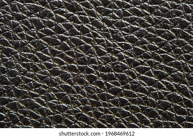 Black with golden highlights artificial leather, dermatin texture macro background pattern for backdrop macro closeup.