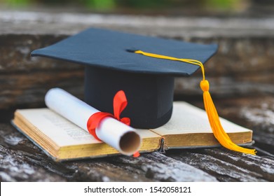 Black graduates hat and yellow tassel place an old book