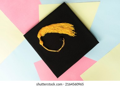 Black graduation cap or hat with yellow tassel on colorful pastel background education mortarboard