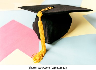 Black graduation cap or hat with yellow tassel on colorful pastel background education mortarboard selective focus soft focus defocused