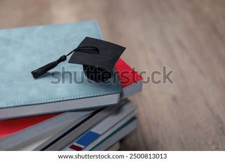 A black graduation cap on a stack of colorful books. Copy space for text. Education and knowledge concept.