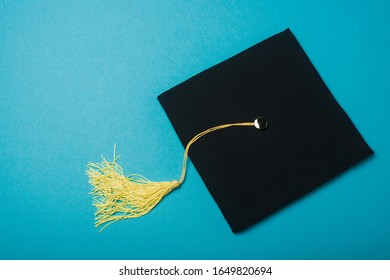 Black graduation cap with tassel brush on blue background