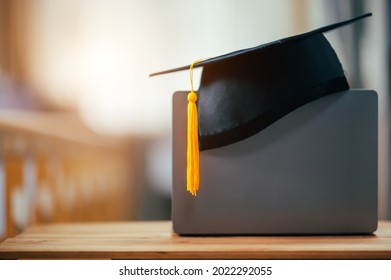 black graduation cap with yellow tassels put on laptop