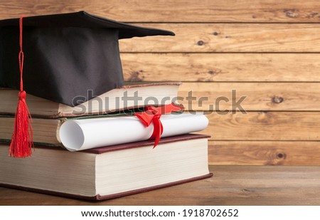 Black graduation hat with diploma and book