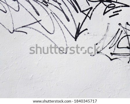 Black graffiti sign on white wall in urban city. Painting on plaster on concrete stucco clean wall. Dirty abandoned art on building. Conceptual image with copy space for text or design.