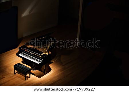 black grand piano at spot light in dark room