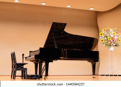 A Black Grand Piano With Two Chairs On Stage