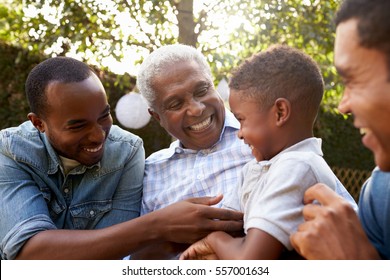 Black Grandfather, Sons And Grandson Talking In A Garden