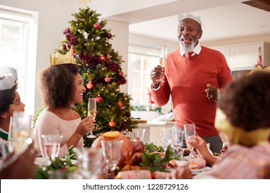 Black Grandfather Standing To Make A Speech And A Toast At The Head Of The Family Christmas Dinner Table, Front View