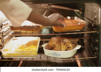 Black Grandmother Cooking Thanksgiving Soul Food Dinner With Love. Mac And Cheese, Candied Yams, And Chicken In The Over Ready To Celebrate With The Family