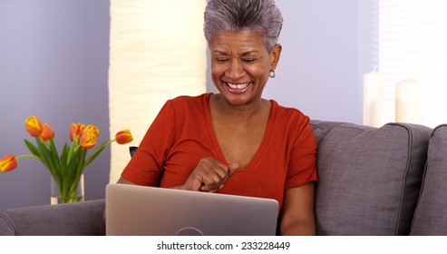 Black Grandmother Laughing And Talking On Laptop