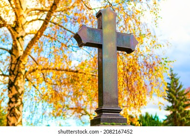 Black Granite Cross On The Graveyard . Black Cross On Headstone . Autumn In Cemetery 