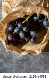 Black Grapes In A Brown Paper Bag. Eco Friendly Recycle Packaging To Help Tackle Global Warming